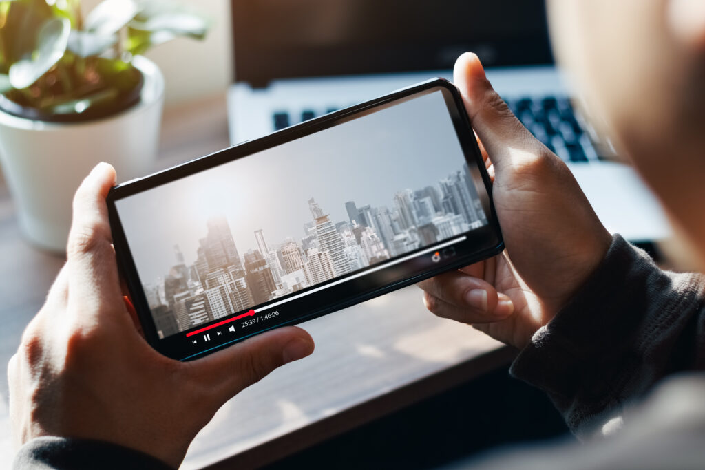 Online movie stream with smartphone. Young man  watching film on mobile phone with imaginary video player service.